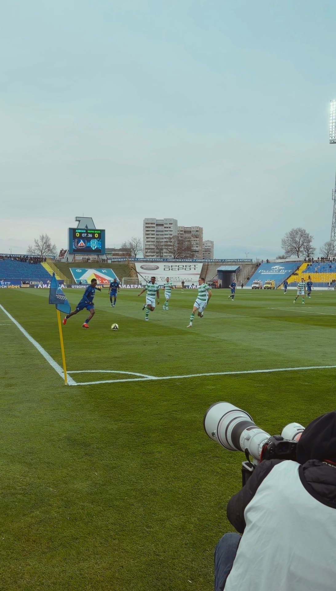 A photographer with a long lens watches a corner kick during a European football match